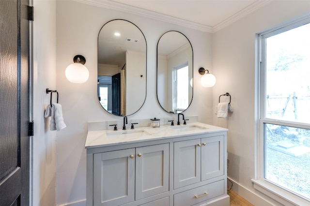 bathroom featuring crown molding, plenty of natural light, visible vents, and a sink