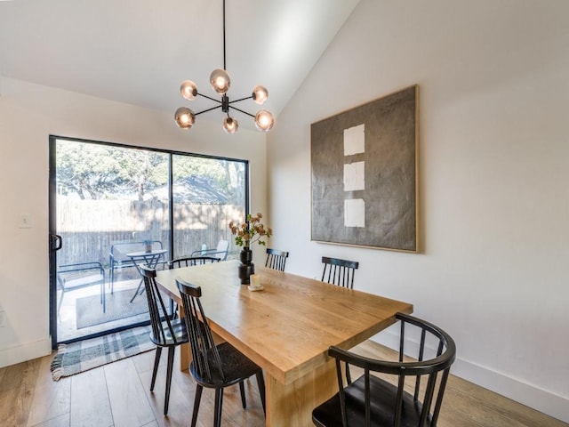 dining area with lofted ceiling, an inviting chandelier, wood finished floors, and baseboards