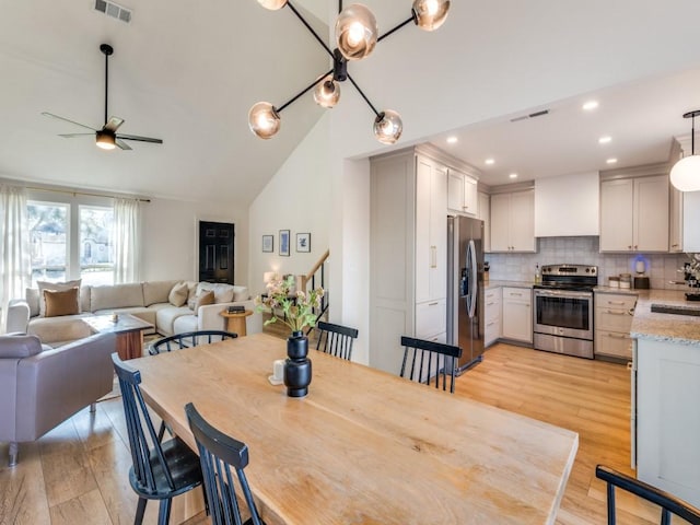 dining room with lofted ceiling, light wood finished floors, ceiling fan, and visible vents