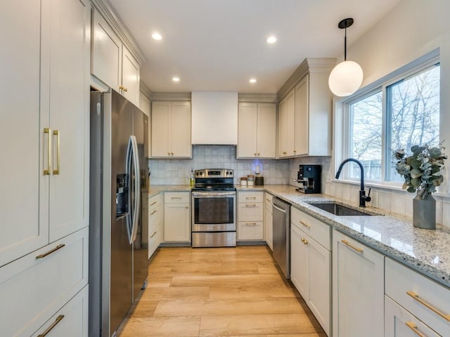 kitchen featuring tasteful backsplash, light wood-style flooring, custom exhaust hood, stainless steel appliances, and a sink