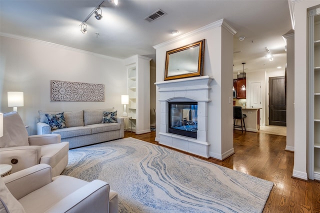 living area featuring visible vents, wood finished floors, baseboards, crown molding, and a multi sided fireplace