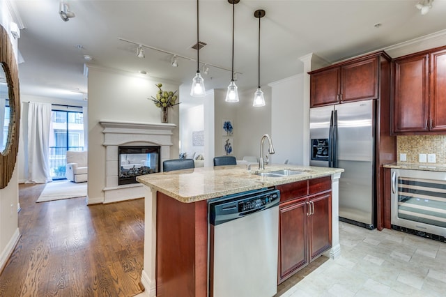 kitchen featuring tasteful backsplash, reddish brown cabinets, wine cooler, stainless steel appliances, and a sink
