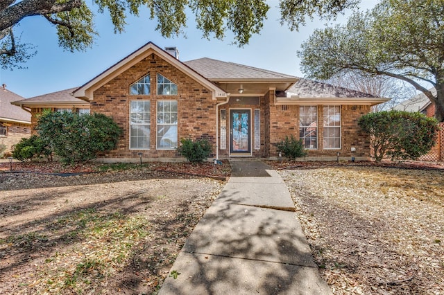 view of front of home featuring brick siding and roof with shingles