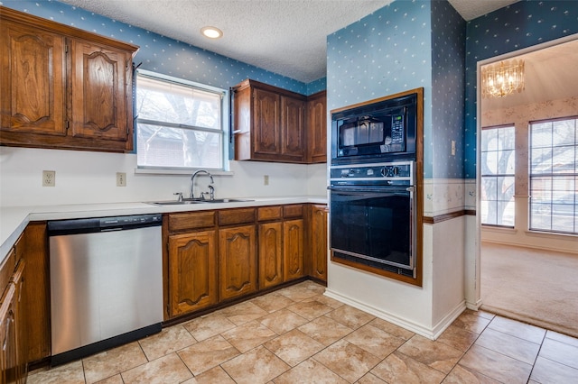 kitchen with a sink, a textured ceiling, black appliances, and wallpapered walls