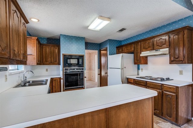 kitchen featuring wallpapered walls, under cabinet range hood, light countertops, black appliances, and a sink