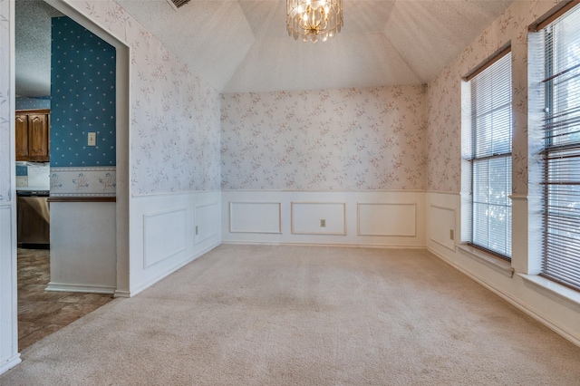 empty room with lofted ceiling, a textured ceiling, carpet flooring, and wallpapered walls