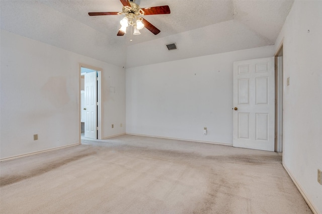 unfurnished room with light colored carpet, visible vents, a ceiling fan, vaulted ceiling, and a textured ceiling