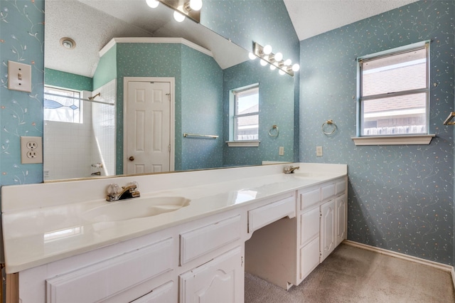 bathroom featuring a sink, a textured ceiling, and wallpapered walls