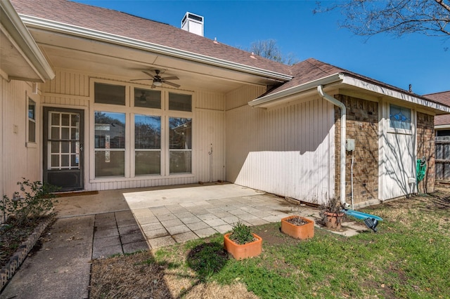 back of property featuring roof with shingles, a patio, a chimney, brick siding, and ceiling fan