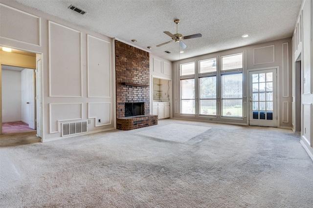 unfurnished living room with carpet, a brick fireplace, visible vents, and a decorative wall