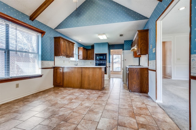 kitchen featuring wallpapered walls, lofted ceiling with beams, a peninsula, light countertops, and black appliances