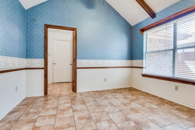 unfurnished room with vaulted ceiling with beams, baseboards, a wealth of natural light, and wallpapered walls