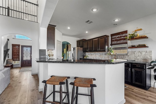 kitchen with light wood finished floors, a breakfast bar, decorative backsplash, and stainless steel fridge with ice dispenser