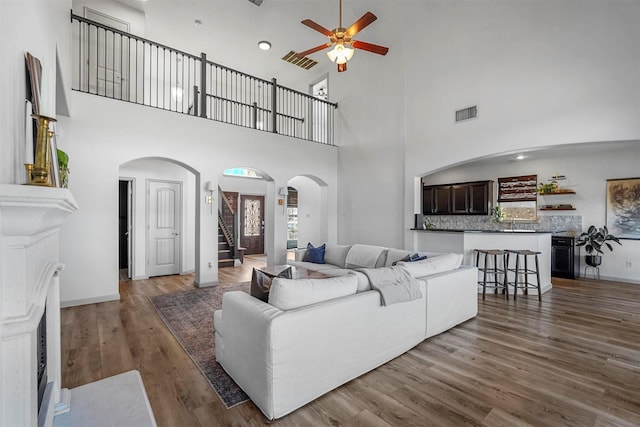 living room with stairway, visible vents, arched walkways, and wood finished floors