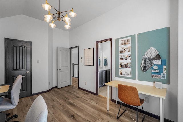 office area featuring light wood-style floors, baseboards, a chandelier, and vaulted ceiling