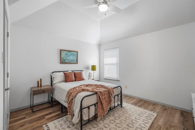 bedroom featuring a ceiling fan, lofted ceiling, baseboards, and wood finished floors