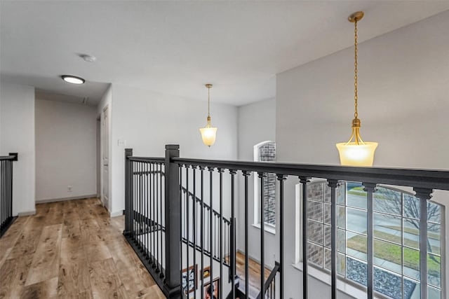 hallway featuring wood finished floors, an upstairs landing, and baseboards