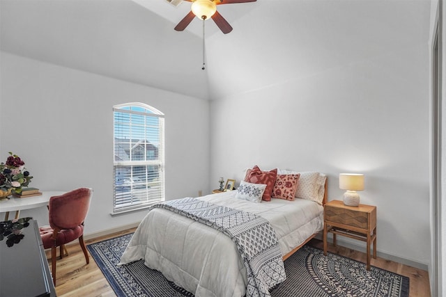 bedroom featuring light wood-style floors, ceiling fan, baseboards, and vaulted ceiling