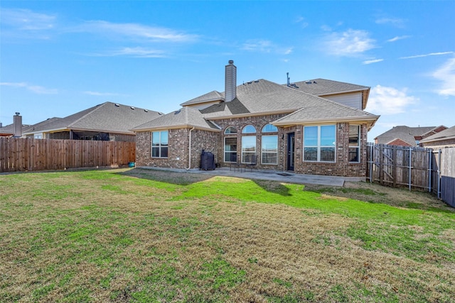 back of property featuring a fenced backyard, a chimney, a lawn, and brick siding