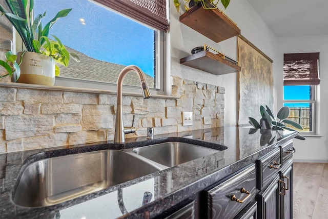 kitchen featuring dark stone counters, a sink, and wood finished floors