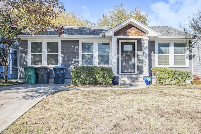 bungalow featuring a shingled roof and a front lawn