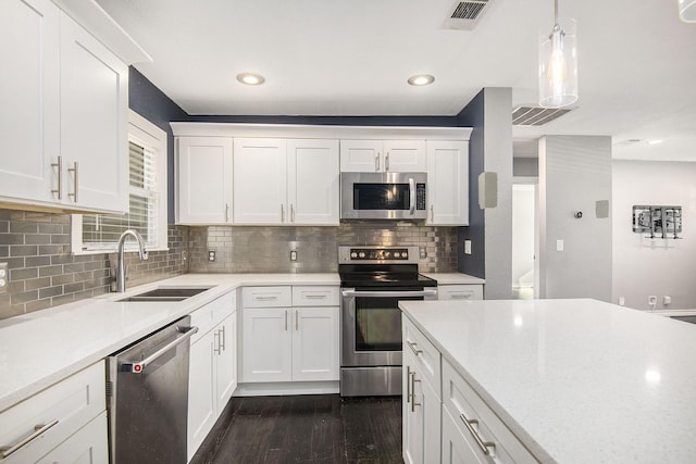 kitchen featuring dark wood finished floors, stainless steel appliances, light countertops, visible vents, and a sink