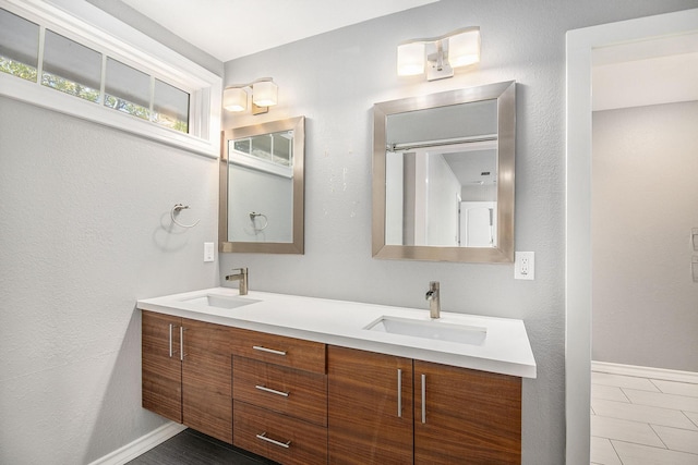 full bath featuring double vanity, baseboards, and a sink