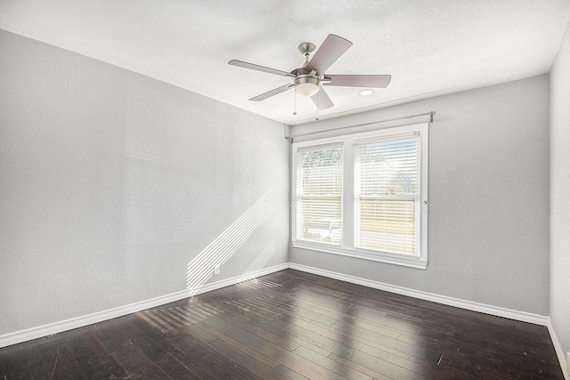 empty room with dark wood-style floors, baseboards, and a ceiling fan