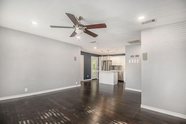 unfurnished living room with dark wood-style floors, a ceiling fan, visible vents, and baseboards