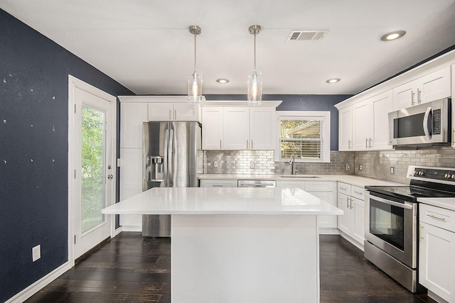 kitchen with dark wood-type flooring, a sink, visible vents, appliances with stainless steel finishes, and backsplash