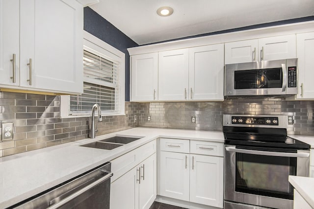 kitchen featuring stainless steel appliances, light countertops, backsplash, white cabinetry, and a sink