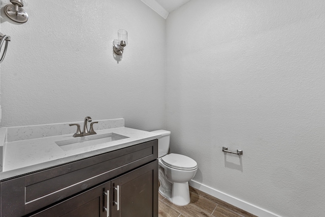 half bathroom featuring baseboards, vanity, toilet, and wood finished floors