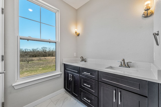 bathroom featuring marble finish floor, a sink, baseboards, and double vanity