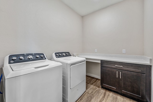 washroom with light wood-type flooring, cabinet space, and separate washer and dryer