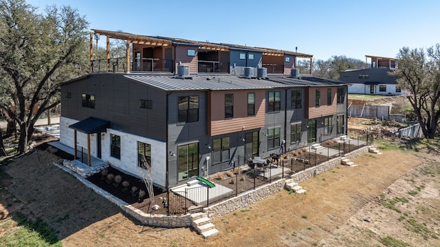 back of property featuring a balcony, metal roof, a standing seam roof, fence, and a patio area