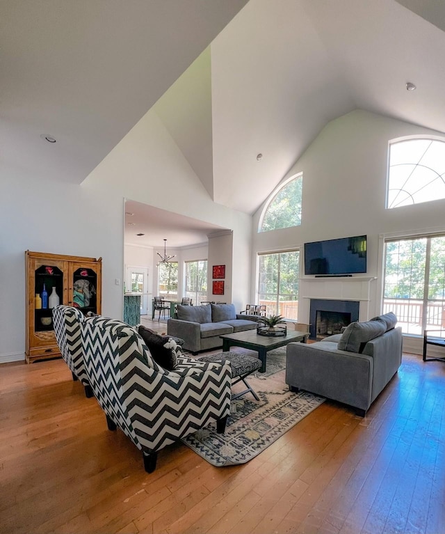 living area with high vaulted ceiling, a fireplace, and hardwood / wood-style flooring