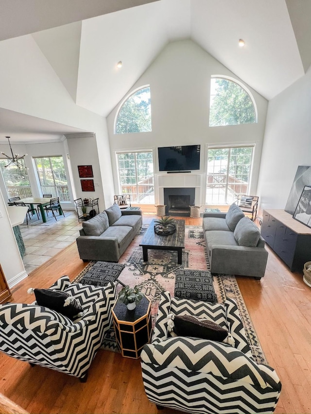 living room with high vaulted ceiling, wood finished floors, a tile fireplace, and a healthy amount of sunlight