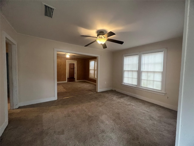 carpeted empty room featuring baseboards, visible vents, ceiling fan, and ornamental molding