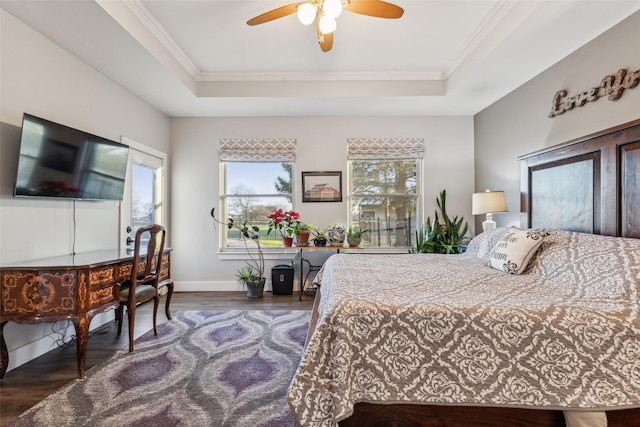 bedroom with ornamental molding, wood finished floors, and a raised ceiling