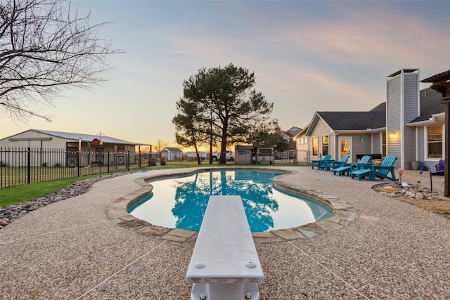 view of pool featuring an outbuilding, fence, a diving board, a fenced in pool, and a patio area