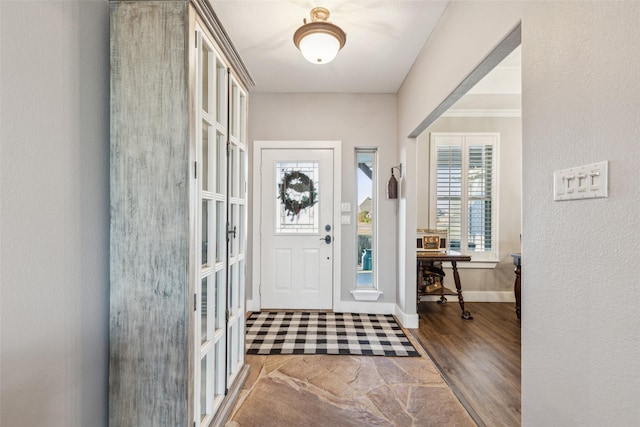 entryway with crown molding, baseboards, and wood finished floors