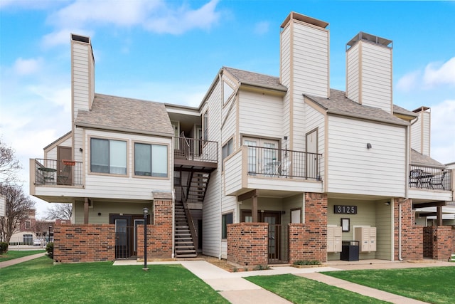 exterior space with stairway, brick siding, a chimney, and a front lawn