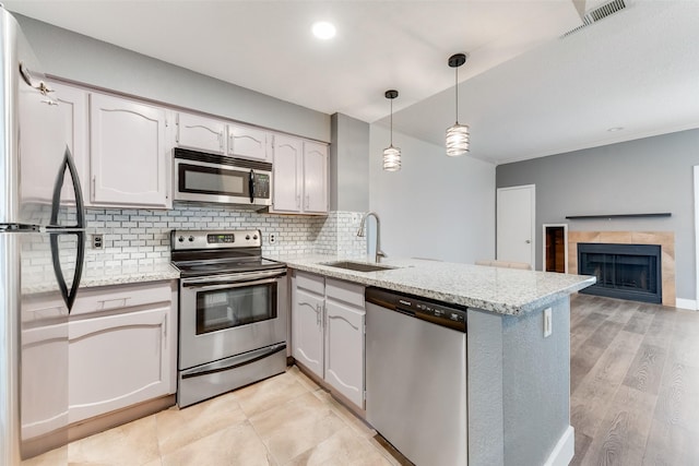 kitchen featuring a peninsula, a sink, visible vents, appliances with stainless steel finishes, and tasteful backsplash