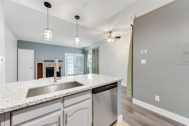 kitchen with hanging light fixtures, ornamental molding, a sink, light wood-type flooring, and dishwasher