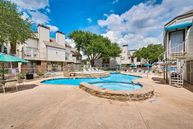 pool with a community hot tub, fence, a residential view, and a patio