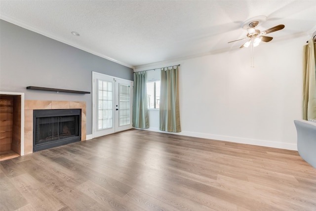 unfurnished living room with baseboards, ornamental molding, wood finished floors, a textured ceiling, and a fireplace