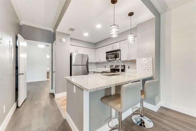 kitchen with tasteful backsplash, visible vents, appliances with stainless steel finishes, a peninsula, and white cabinetry