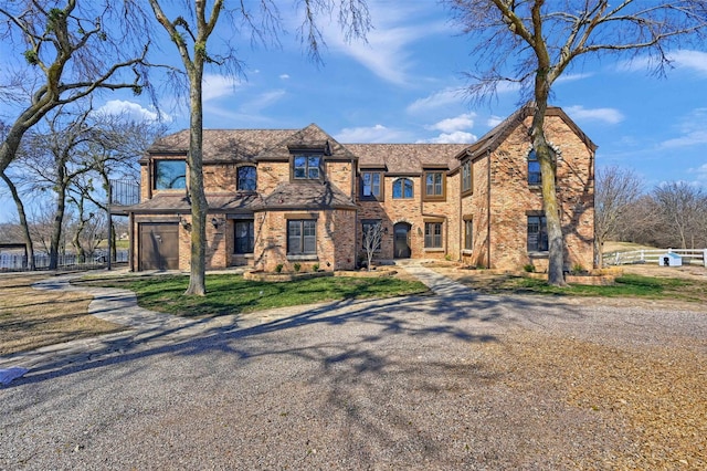 view of front of home featuring a garage, driveway, brick siding, and fence