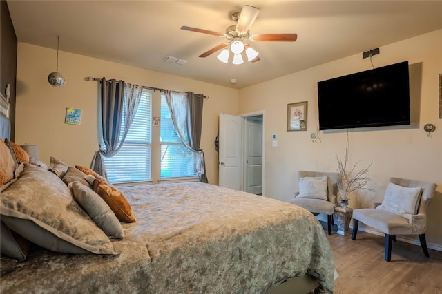 bedroom with ceiling fan, visible vents, and wood finished floors