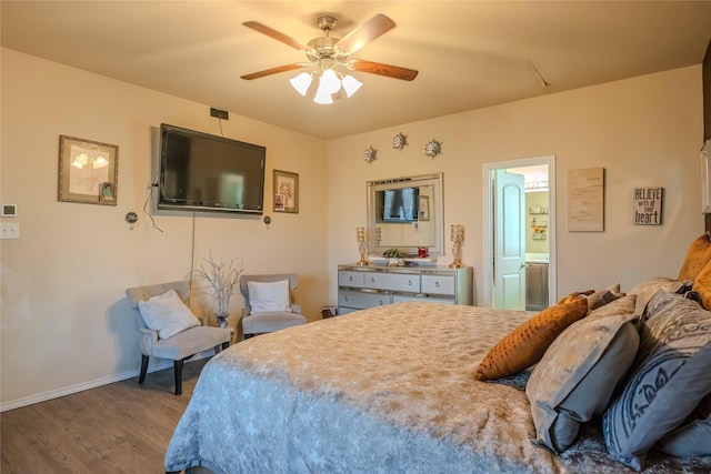 bedroom with ceiling fan, ensuite bath, wood finished floors, and baseboards